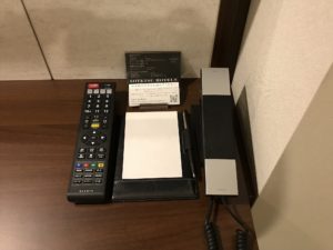 相鉄フレッサイン 東京六本木 ダブルルーム デスク フロント連絡用の電話とメモ、テレビのリモコンがあります