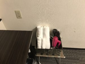 ホテルウィングインターナショナル新宿 シングルルーム デスク脇 ACコンセントとタオル類、ドライヤー、スリッパがあります