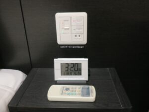 天然温泉間門の湯 ホテルドーミーインPREMIUM下関 ダブルルーム 枕元 照明のスイッチと目覚まし時計、ACコンセントがあります