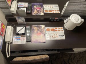 アパホテル&リゾート 東京ベイ幕張 ウェストウィング ツインルーム デスク上 電話機、メモ帳、テレビのリモコン、有線LANコネクタ、ACコンセント、デスク照明のスイッチ、電気ポットがあります