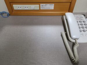 秋田天然温泉 ルートイングランティア秋田 SPA RESORT ダブルルーム デスク上 ACコンセント、デスク灯のスイッチ、電話、有線LANがあります