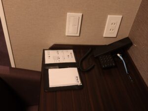 ドーミーイン鹿児島 ダブルルーム テーブル脇 照明のスイッチとACコンセントがあります